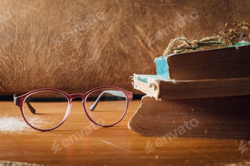 Preview: Eyeglasses and Stack of Vintage Books on Table