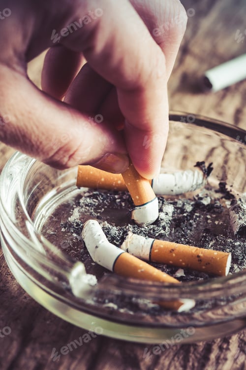Preview: Crumpled Cigarette In Hand With Ashtray On Wooden Table,Quit Smoking