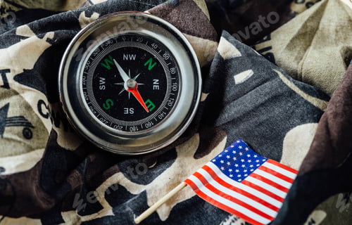 Preview: Old Magnetic Compass And Us Flag On A Camouflage Fabric Of War.