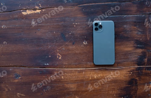 Preview: Back Smartphone On Wooden Desktop. Top View