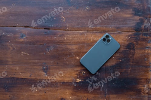 Preview: Back Smartphone On Wooden Desktop. Top View