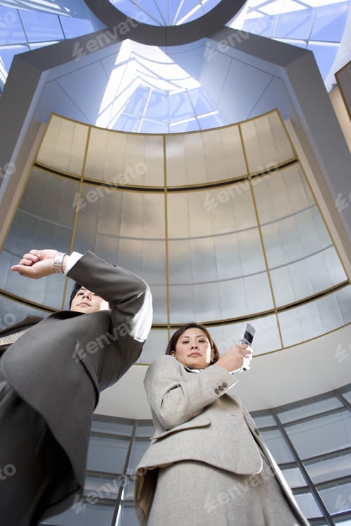 Preview: Businessman And Woman Standing Below Skylight In Airport, Man Checking Time On Wristwatch, Woman