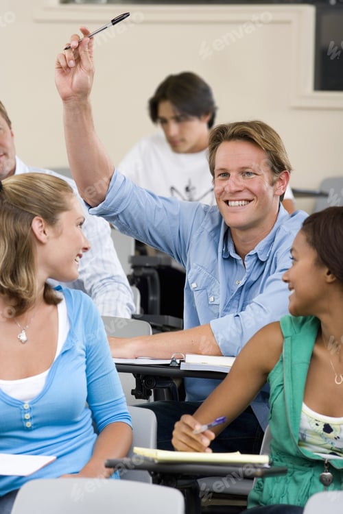 Preview: Students In Classroom, Teenage Girls (16-18) Looking At Teenage Boy (16-18) With Arm Raised