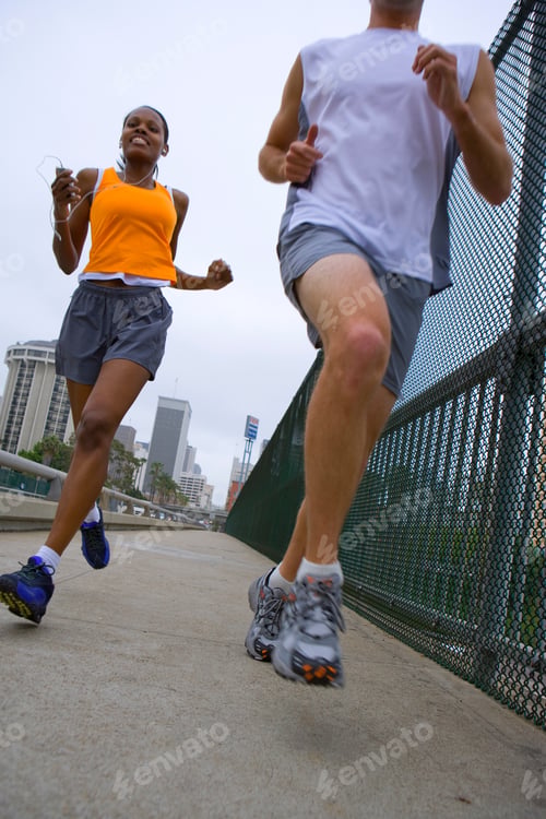 Preview: Active Couple Exercising Running By Fence In City
