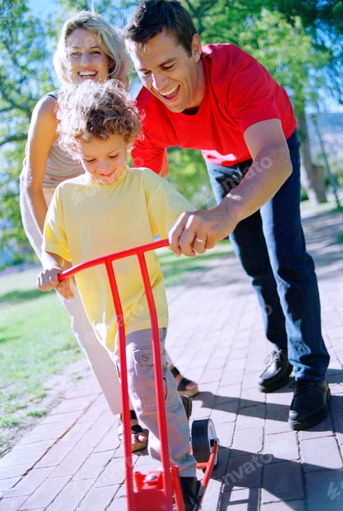 Preview: Father And Mother Helping Son Learning To Ride Push Scooter Outdoors