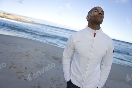Preview: Young Man With Eyes Closed On Beach, Hands In Pockets