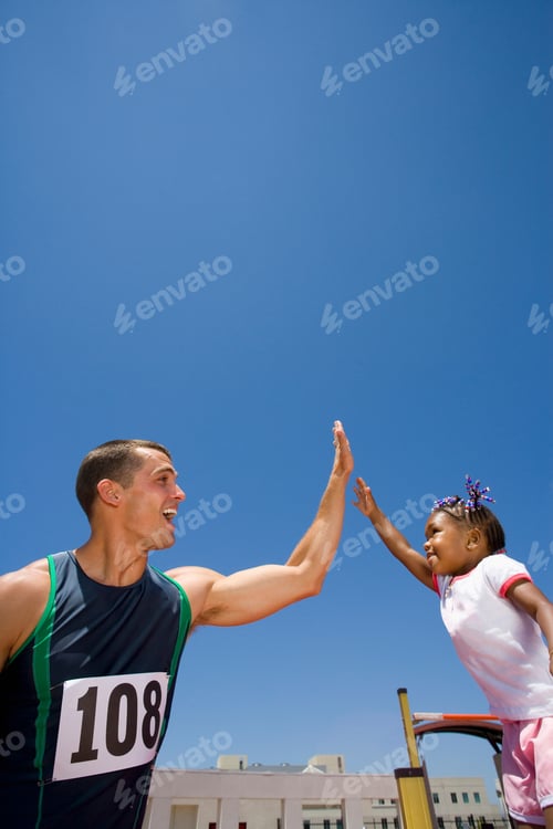 Preview: Male Athlete Giving Young Girl High Five On Athletics Track