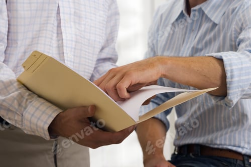 Preview: Two Businessmen Looking At Document In File, Close-Up, Mid-Section