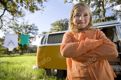 Preview: Girl With Arms Crossed By Camper Van In Field, Smiling, Low Angle View