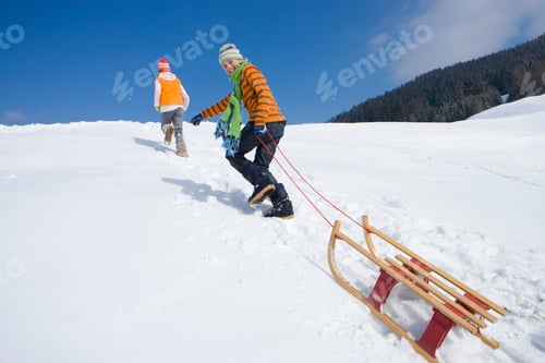 Preview: Children On Winter Vacation Pulling Sled Up Snowy Mountain Smiling At Camera