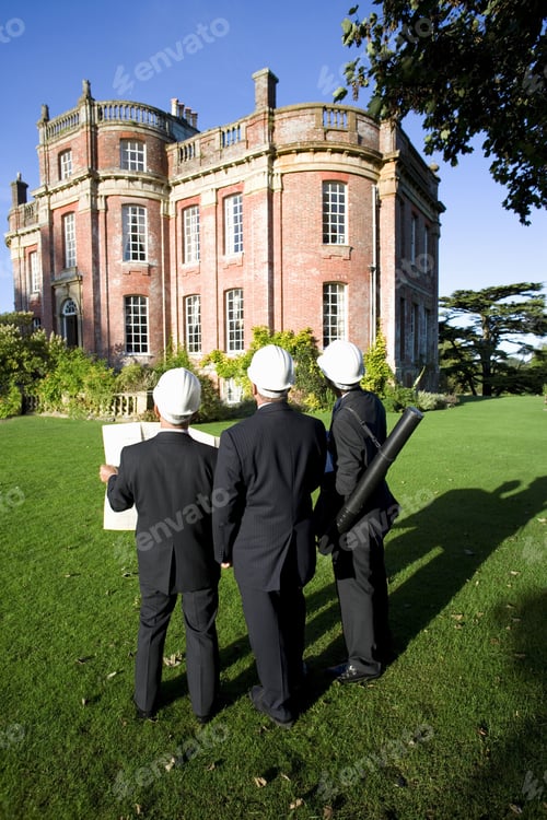 Preview: Group Of Businessmen In Hardhats With Blueprint Looking At Manor House, Rear View