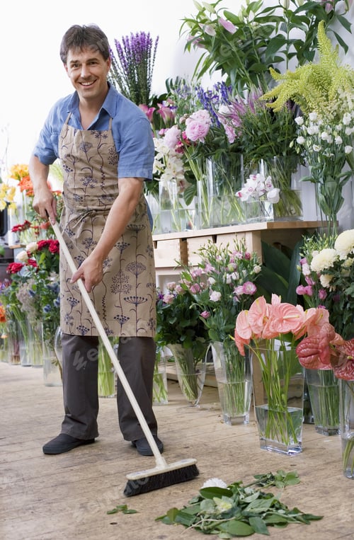 Preview: Male Florist In Apron Standing In Flower Shop, Sweeping Floor With Broom, Smiling, Portrait