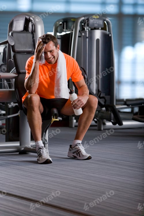 Preview: Active Man With Towel After Exercising On Equipment In Health Club