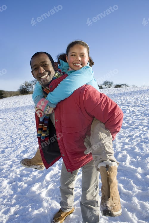 Preview: Father Giving Daughter Piggyback Ride In Snowy Field