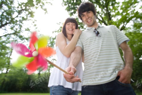 Preview: Young Couple Outdoors Holding Toy Windmill At Camera