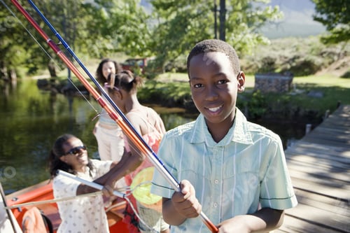 Preview: Family Standing In Motorboat, Focus On Boy (8-10) Standing On Lake Jetty, Holding Fishing Rod