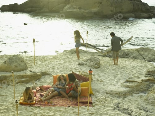 Preview: High Angle View Of A Young Man Playing The Guitar With His Friends On The Beach
