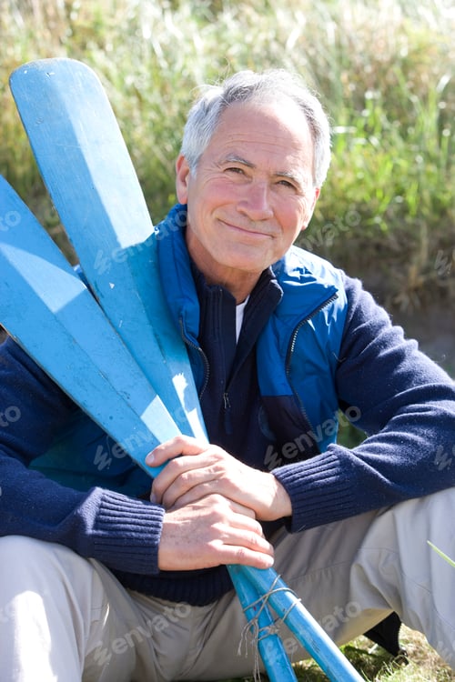 Preview: Portrait Of Mature Man Holding Oars On Beach In Autumn