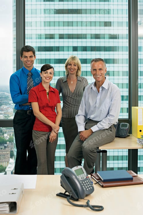 Preview: Portrait Of Four Smiling Office Business Colleagues In Team Standing By Window Looking At Camera