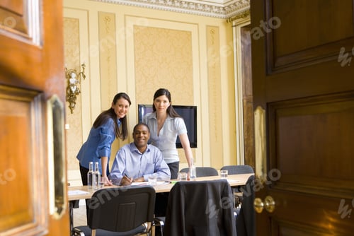 Preview: Businessman At Table Flanked By Female Colleagues, Smiling, Portrait, View Through Doors