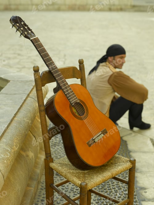 Preview: Guitar On A Chair With A Young Man Sitting On Steps