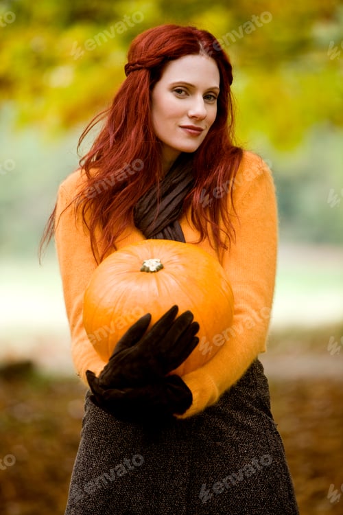 Preview: Beautiful Woman With Red Hair Holding Pumpkin Outdoors Looking At Camera