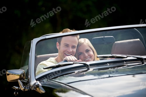 Preview: Young Couple Driving Classic Convertible Black Sports Car Smiling At Camera