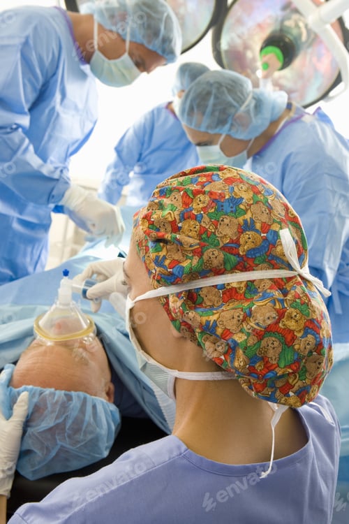 Preview: Surgeons Attending To Patient On Bed In Operating Room, Elevated View