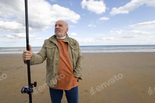 Preview: Senior Man With Fishing Rod On Beach, Hand In Pocket, Low Angle View