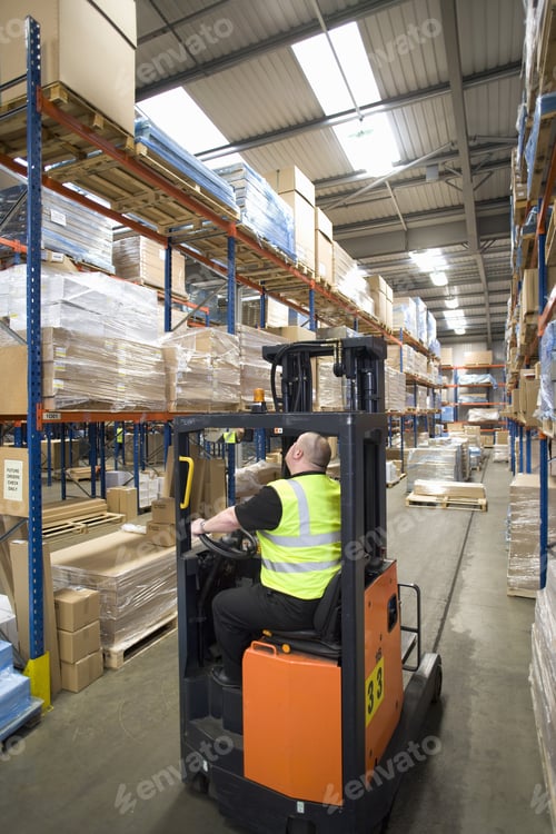 Preview: Warehouse Worker Operating Forklift And Looking Up At Shelves