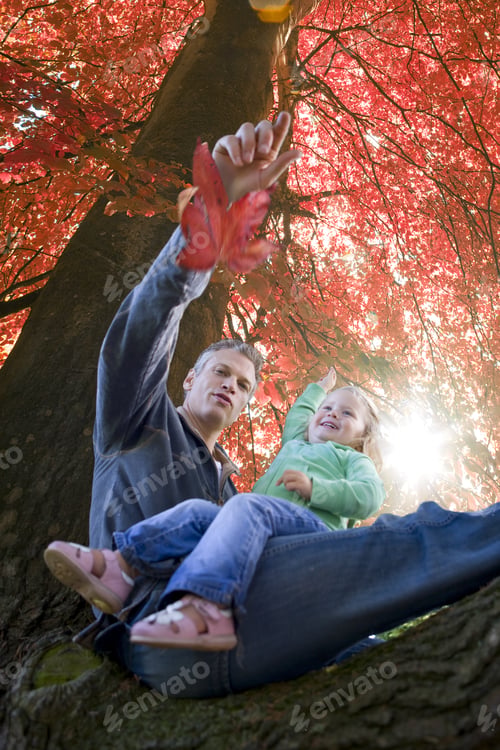 Preview: Father And Daughter Sitting In Tree With Autumn Leaves
