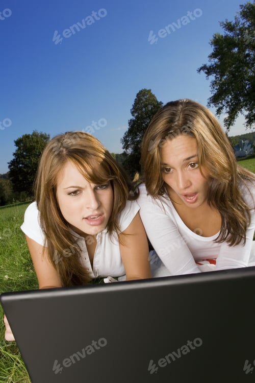 Preview: Two Friends Lying On The Grass And Using A Laptop.