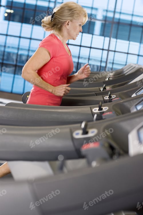 Preview: Senior Woman Running On Treadmill In Health Club
