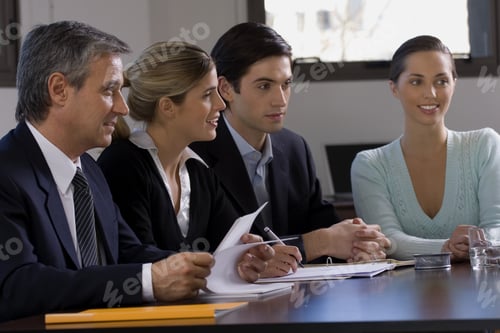 Preview: Four Business Executives Sitting At A Conference Table In A Conference Room