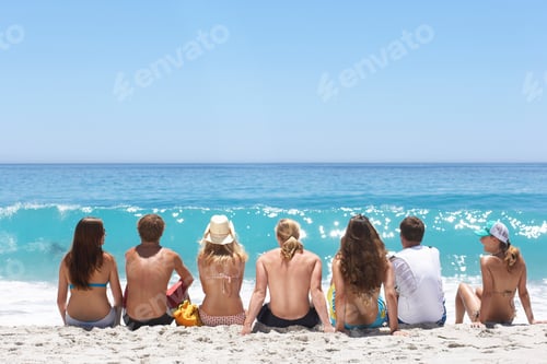 Preview: Group Of Teenagers Sitting On Sandy Summer Vacation Beach Looking At Horizon Over Sea Waves