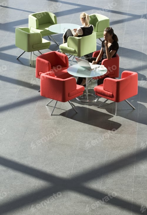 Preview: Two Businesswomen Sitting At Tables In An Office Building