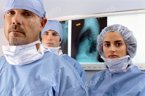 Preview: Hospital Surgical Team In Scrubs Standing In Front Of X-Rays Looking At Camera