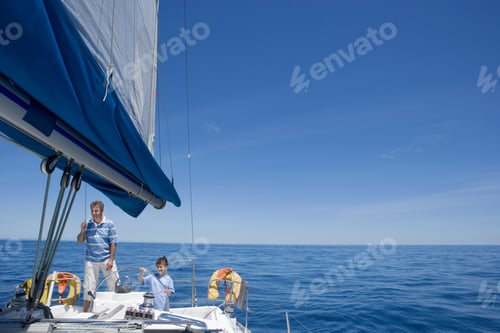 Preview: Father And Son (8-10) Standing At Helm Of Sailing Boat Out To Sea, Boy Steering, Smiling