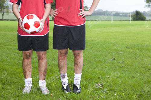 Preview: Portrait Of Muddy Soccer Players Holding Ball On Field
