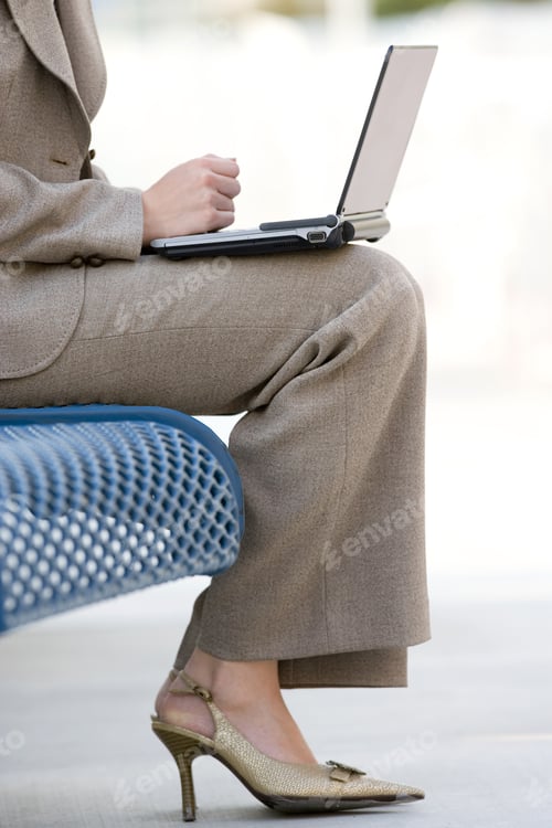 Preview: Businesswoman In Suit And High Heels Using Laptop On Pavement Bench, Low Section, Profile