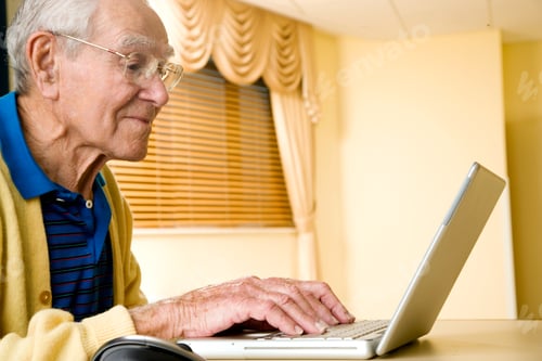 Preview: Senior Man Sitting At Home Using A Laptop At Table