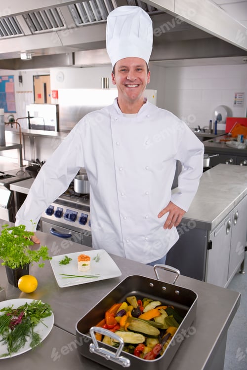 Preview: Chef Standing With Vegetables In Commercial Kitchen Smiling At Camera