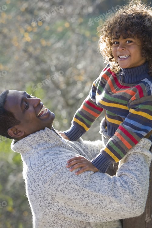 Preview: Laughing Father Lifting Smiling Son Outdoors
