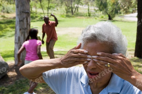 Preview: Hide And Seek In Summer Park With Grandmother Covering Eyes And Grandfather And Grandchildren