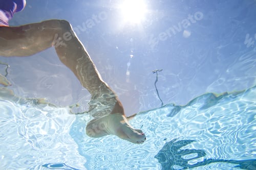 Preview: Woman Dipping Foot In Swimming Pool, Underwater View, Low Section (Sun Flare)