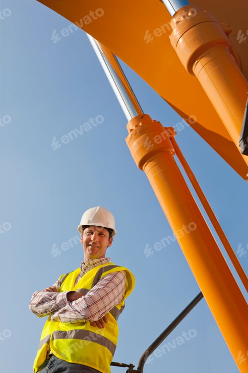 Preview: Construction Worker In Hard Hat With Plant Machinery Smiling At Camera