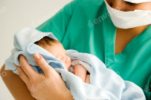 Preview: Maternity Nurse Wearing Scrubs Holding Newborn Baby Wrapped In Blanket