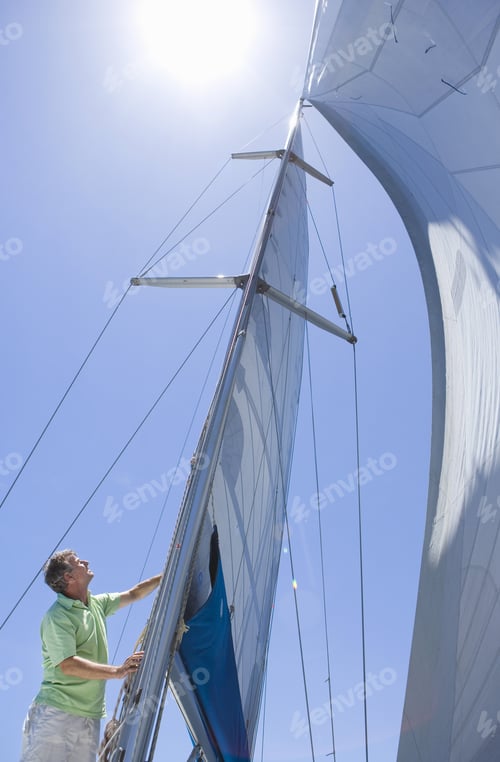 Preview: Man Standing On Deck Of Sailing Boat Out To Sea, Adjusting Sail Mast Rigging, Side View, Low Angle