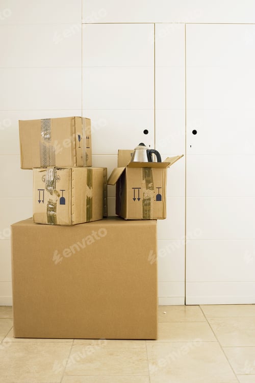 Preview: Stack Of Large And Small Sealed Cardboard Boxes In Room, Kettle In Open Box