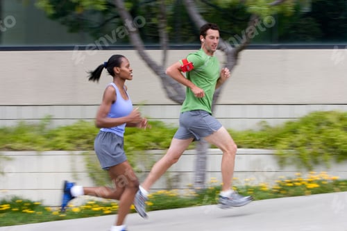 Preview: Action Shot Active Couple Jogging In Urban Setting Listening To Mp3 Player On Armband With Motion